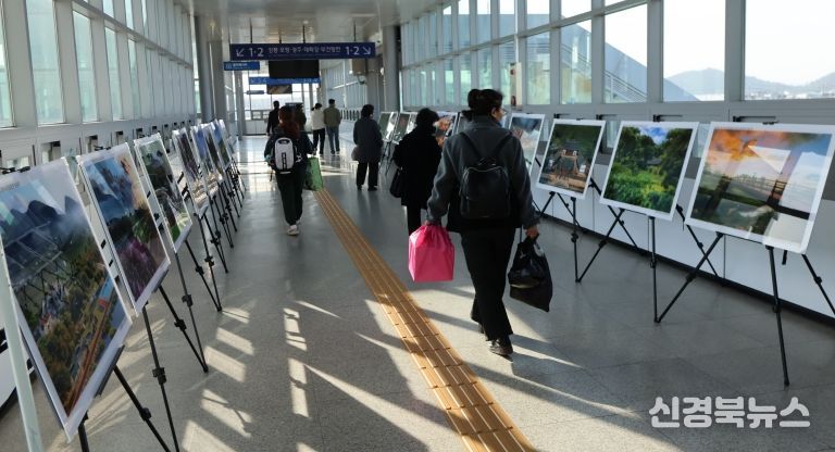 영천역 승강장 입출구 통로에 전시된 제17회 영천관광 전국사진공모전 입상작품을 철도 이용객들이 관람하고 있다.